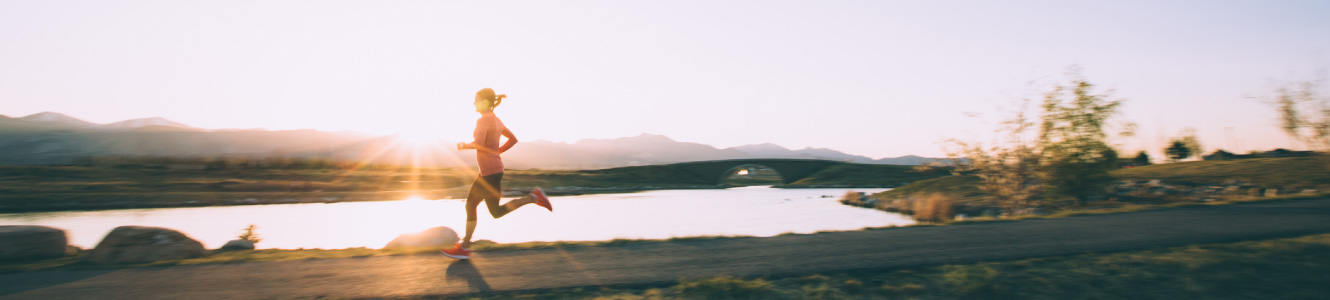 Woman jogging around a lake with the sun setting